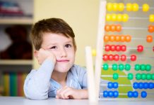 Ein Junge im Grundschul- oder Kindergartenalter schaut skeptisch auf einen Rechenschieber.