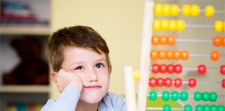 Ein Junge im Grundschul- oder Kindergartenalter schaut skeptisch auf einen Rechenschieber.